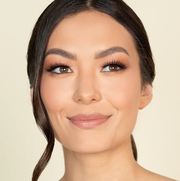 Female model with dark, brown hair wearing Reese Robert Beauty's Faux Fur 2D Feather Effect lashes on light yellow background